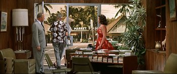 Movie still from “Blue Hawaii” (1961), directed by Norman Taurog – A woman in a red dress walking down a street; Wide shot, Over the shoulder angle