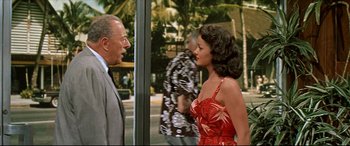 Movie still from “Blue Hawaii” (1961), directed by Norman Taurog – A man and a woman are standing in front of a building; Medium shot, Over the shoulder angle