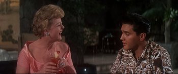 Movie still from “Blue Hawaii” (1961), directed by Norman Taurog – Two women are talking to each other outside; Medium shot, Over the shoulder angle