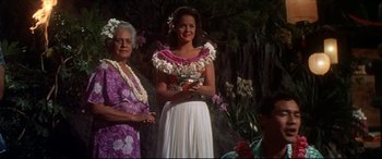 Movie still from “Blue Hawaii” (1961), directed by Norman Taurog – Two women standing next to each other in front of trees and flowers; Medium shot, Low angle