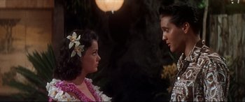 Movie still from “Blue Hawaii” (1961), directed by Norman Taurog – Two people are talking to each other in front of some trees; Medium shot, Over the shoulder angle