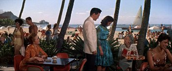 Movie still from “Blue Hawaii” (1961), directed by Norman Taurog – A man and a woman standing next to each other on the beach; Wide shot, Over the shoulder angle