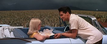 Movie still from “Blue Hawaii” (1961), directed by Norman Taurog – A man and a woman sitting in the back of a car; Medium shot, Over the shoulder angle