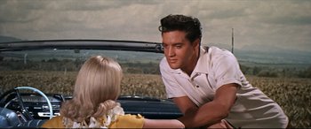 Movie still from “Blue Hawaii” (1961), directed by Norman Taurog – A man and a woman sitting in the back of a car; Medium shot, Over the shoulder angle
