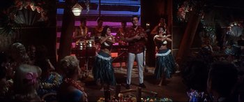 Movie still from “Blue Hawaii” (1961), directed by Norman Taurog – A group of hula dancers and a man standing in front of a crowd of onlookers; Wide shot, Low angle