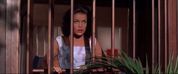Movie still from “Blue Hawaii” (1961), directed by Norman Taurog – A woman standing behind bars looking out of a window; Medium shot, Low angle