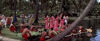 Movie still from “Blue Hawaii” (1961), directed by Norman Taurog – A group of women in pink dresses standing next to each other in the grass; Extreme Wide shot, High angle