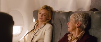 Movie still from “Blue Jasmine” (2013), directed by Woody Allen – A woman sitting in a chair next to another woman; Medium shot, Over the shoulder angle