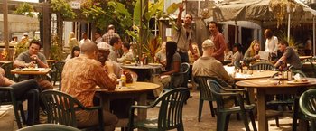 Movie still from “Blue Jasmine” (2013), directed by Woody Allen – A group of people sitting at a table with drinks; Wide shot, Over the shoulder angle
