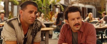 Movie still from “Blue Jasmine” (2013), directed by Woody Allen – A couple of men sitting next to each other on top of a table; Close Up shot, Over the shoulder angle