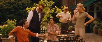 Movie still from “Blue Jasmine” (2013), directed by Woody Allen – A group of people standing around a table; Medium shot, Over the shoulder angle
