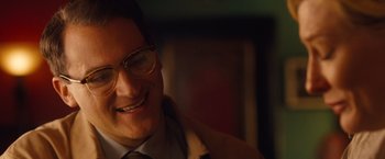 Movie still from “Blue Jasmine” (2013), directed by Woody Allen – A person wearing a suit and glasses; Close Up shot, Over the shoulder angle