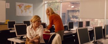 Movie still from “Blue Jasmine” (2013), directed by Woody Allen – Two women in an office setting , one of whom is holding a bag; Medium shot, Over the shoulder angle