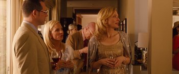 Movie still from “Blue Jasmine” (2013), directed by Woody Allen – A group of people standing in a room holding wine glasses; Medium shot, Over the shoulder angle