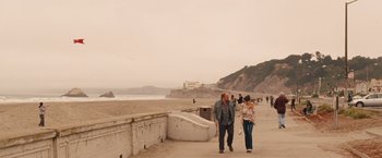 Movie still from “Blue Jasmine” (2013), directed by Woody Allen – A man and a woman walking down a sidewalk near the ocean; Wide shot, High angle