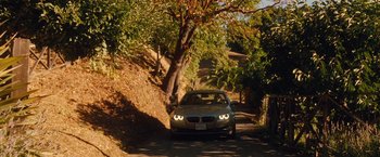 Movie still from “Blue Jasmine” (2013), directed by Woody Allen – A car driving down a road next to a tree; Extreme Wide shot, High angle