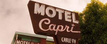Movie still from “Blue Jasmine” (2013), directed by Woody Allen – A motel sign that says " motel capri " and " cable tv "; Wide shot, Low angle