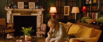 Movie still from “Blue Jasmine” (2013), directed by Woody Allen – A woman sitting on top of a couch in a living room; Medium shot, High angle