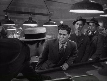 Movie still from “Blues in the Night” (1941), directed by Anatole Litvak – A group of men standing around a pool table in a room; Medium shot, High angle