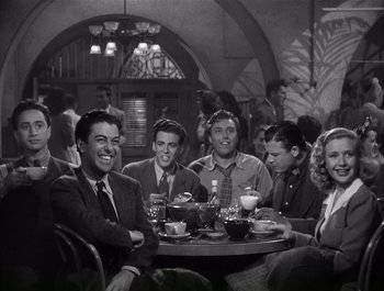 Movie still from “Blues in the Night” (1941), directed by Anatole Litvak – A black and white photo of a group of people sitting at a table; Medium shot, High angle