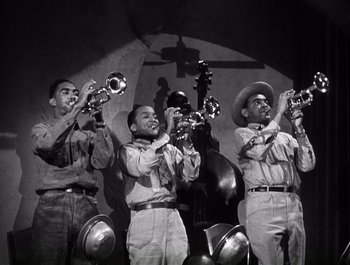 Movie still from “Blues in the Night” (1941), directed by Anatole Litvak – A black and white photo of a group of men playing musical instruments; Medium shot, Low angle