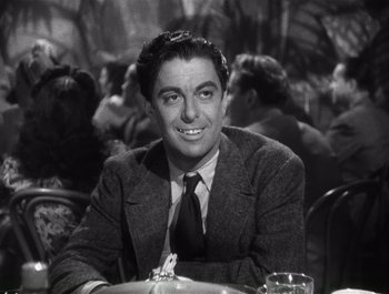 Movie still from “Blues in the Night” (1941), directed by Anatole Litvak – A man sitting at a table in front of other people; Close Up shot, Low angle