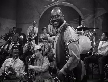 Movie still from “Blues in the Night” (1941), directed by Anatole Litvak – A black - and - white photo of a man with a saxophone; Medium shot, High angle