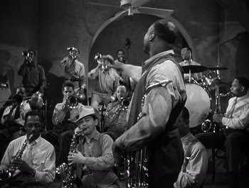 Movie still from “Blues in the Night” (1941), directed by Anatole Litvak – A group of people that are sitting in a room with instruments; Medium shot, High angle