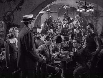 Movie still from “Blues in the Night” (1941), directed by Anatole Litvak – A group of people sitting around a table; Wide shot, High angle