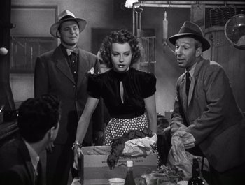 Movie still from “Blues in the Night” (1941), directed by Anatole Litvak – A group of people standing around a table; Medium shot, Low angle
