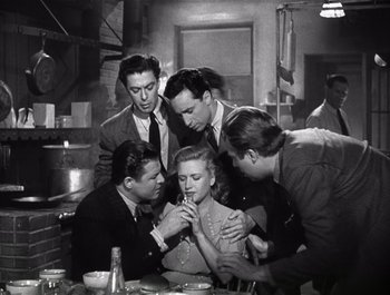 Movie still from “Blues in the Night” (1941), directed by Anatole Litvak – A group of men standing around a woman; Medium shot, High angle