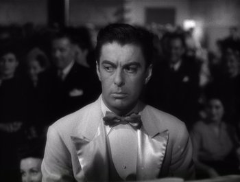 Movie still from “Blues in the Night” (1941), directed by Anatole Litvak – A black and white photo of a man in a suit and bow tie; Close Up shot, Low angle