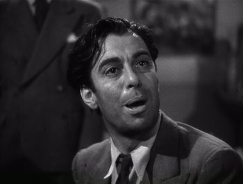 Movie still from “Blues in the Night” (1941), directed by Anatole Litvak – Black and white photograph of a man wearing a suit and tie; Close Up shot, Low angle