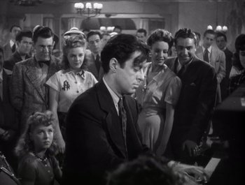 Movie still from “Blues in the Night” (1941), directed by Anatole Litvak – An old photo of a man playing piano in front of a crowd; Medium shot, Low angle