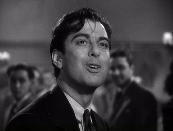 Movie still from “Blues in the Night” (1941), directed by Anatole Litvak – A black and white photo of a man in a suit and tie; Close Up shot, Low angle