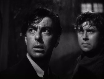 Movie still from “Blues in the Night” (1941), directed by Anatole Litvak – A man and a woman standing next to each other in front of trees; Close Up shot, Low angle