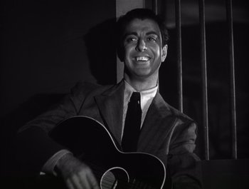 Movie still from “Blues in the Night” (1941), directed by Anatole Litvak – A black and white photo of a man holding a guitar; Close Up shot, Low angle