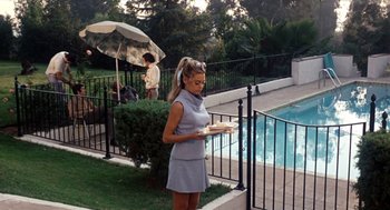 A woman standing in front of a swimming pool holding food