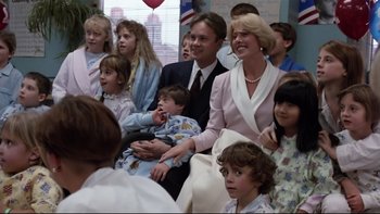Movie still from “Bob Roberts” (1992), directed by Tim Robbins – A large group of people gathered together in a room; Medium shot, Over the shoulder angle