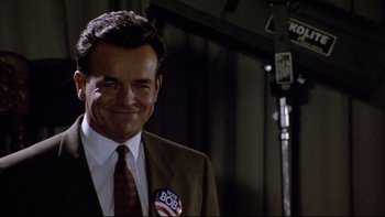 Movie still from “Bob Roberts” (1992), directed by Tim Robbins – A man in a suit and tie with a vote button on his lapel; Close Up shot, Low angle