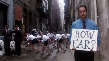 Movie still from “Bob Roberts” (1992), directed by Tim Robbins – A man holding a sign standing in front of a group of people; Wide shot, Low angle