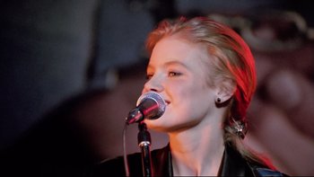 Movie still from “Bob Roberts” (1992), directed by Tim Robbins – A woman is singing into a microphone; Close Up shot, Low angle