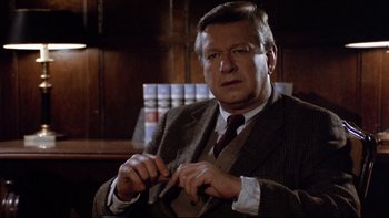 Movie still from “Bob Roberts” (1992), directed by Tim Robbins – An older man wearing a suit and tie in an office setting; Close Up shot, Over the shoulder angle