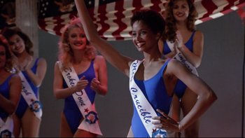 Movie still from “Bob Roberts” (1992), directed by Tim Robbins – A group of women in blue bathing suits holding hands in the air; Medium shot, Low angle