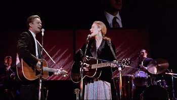 Movie still from “Bob Roberts” (1992), directed by Tim Robbins – A man and a woman singing into microphones; Medium shot, Low angle
