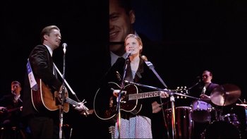 Movie still from “Bob Roberts” (1992), directed by Tim Robbins – A woman singing into a microphone on a stage; Medium shot, Low angle