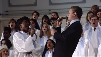 Movie still from “Bob Roberts” (1992), directed by Tim Robbins – A group of young people singing in front of a microphone; Medium shot, Low angle