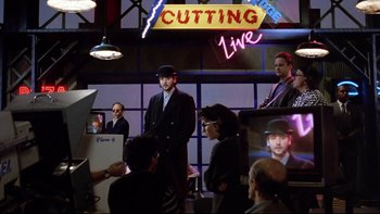 Movie still from “Bob Roberts” (1992), directed by Tim Robbins – A group of people standing in front of a neon sign; Medium shot, Over the shoulder angle
