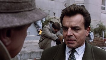 Movie still from “Bob Roberts” (1992), directed by Tim Robbins – A person wearing a suit and tie; Close Up shot, Over the shoulder angle