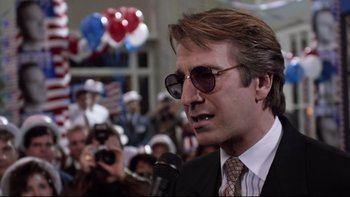 Movie still from “Bob Roberts” (1992), directed by Tim Robbins – A man in a suit and tie holding a microphone; Close Up shot, Low angle